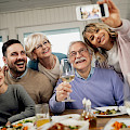 © Drazen Zigic | freepik.com | (Low angle view of happy extended family having fun while taking selfie after lunch at dining table)